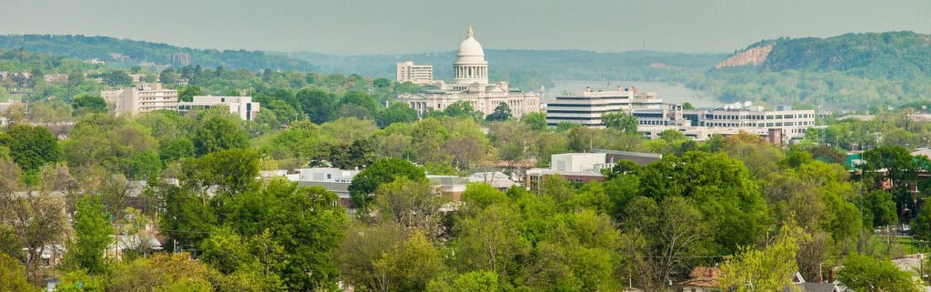 Lush green trees and cityscape with Capitol dome in the background, highlighting urban education initiatives and community engagement by Complete College America.