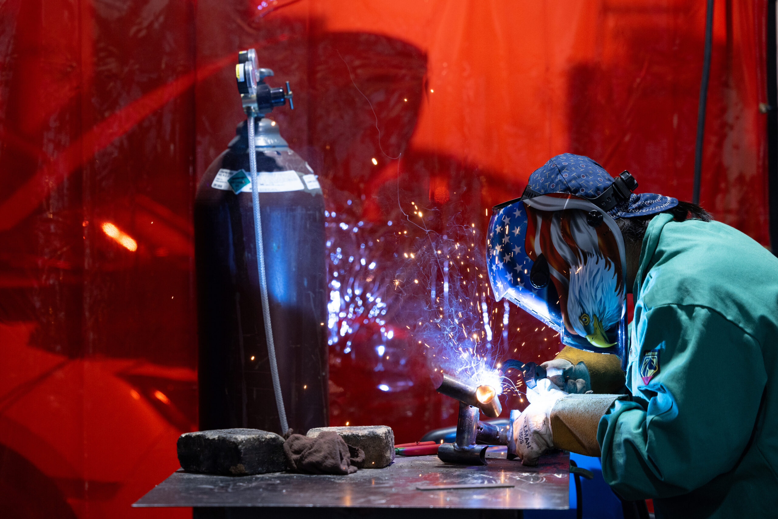 Asian female instructor welding in in auto shop on a college campus.