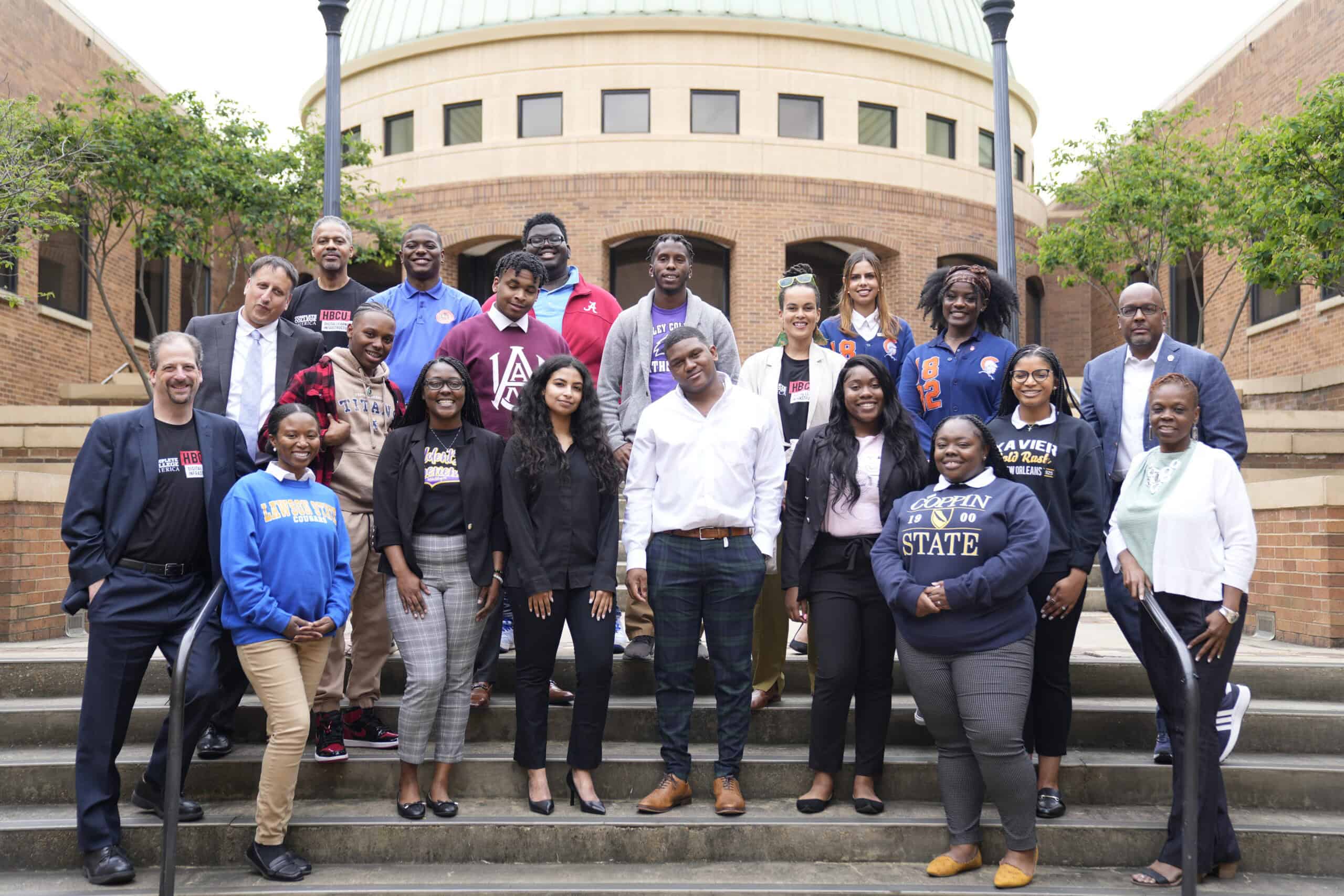 Diverse group of college students and faculty in front of university building, promoting higher education and college success initiatives.