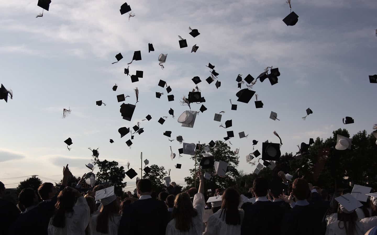Graduates celebrating at graduation ceremony with caps in the air, emphasizing higher education success and achievement.