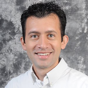 Diverse smiling man in professional attire promoting higher education and college success.
