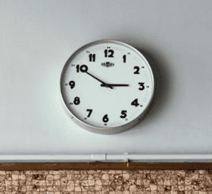 Clock on a wall showing 9:50, modern round wall clock, time management in education, Complete College America initiative, focusing on student success and retention.