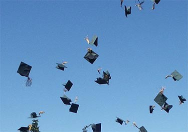 Graduates' caps and gowns being tossed into the sky during a celebration at graduation ceremony.
