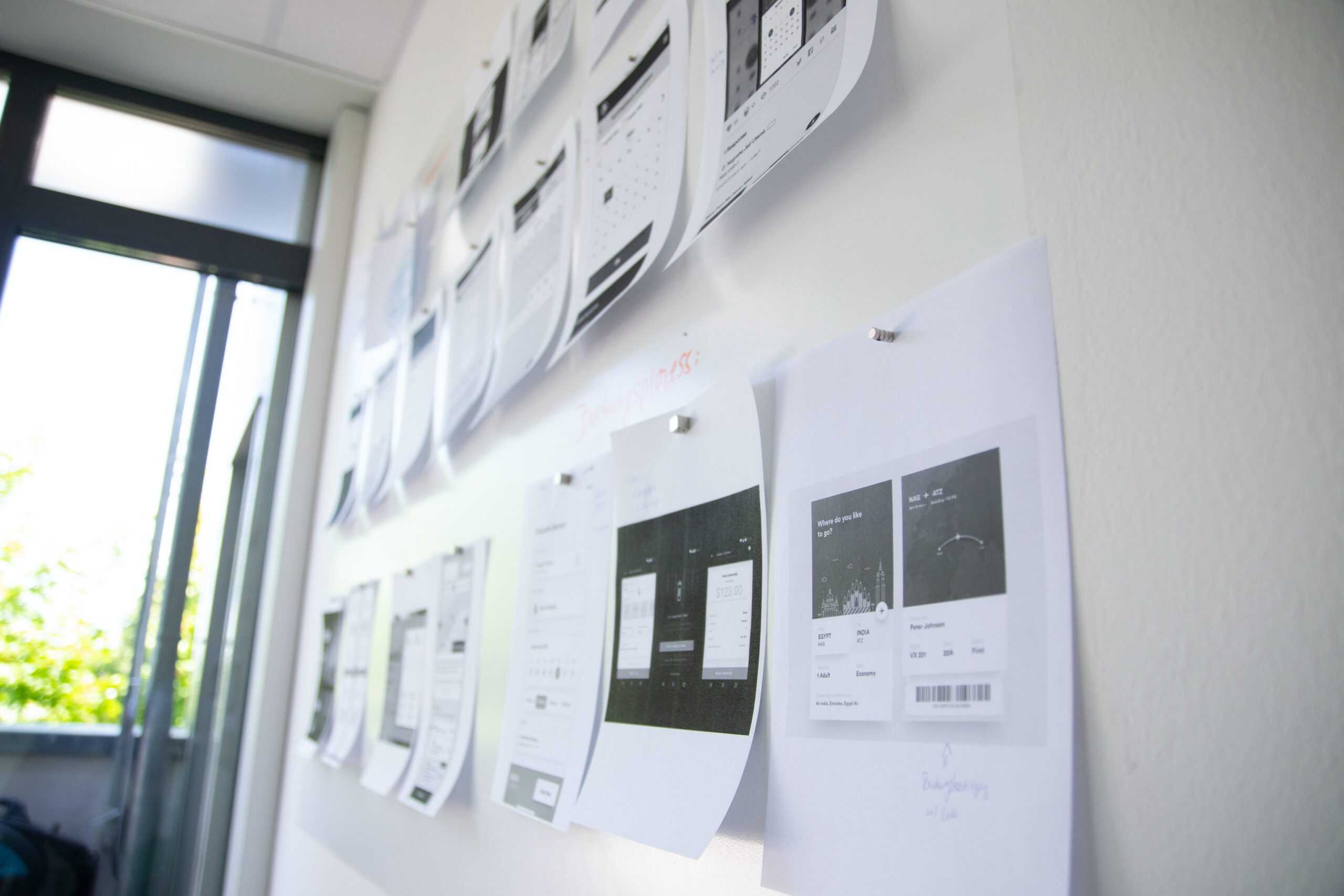 Focused on student success and higher education strategies, the image shows a whiteboard with printed project plans and wireframes related to college or university program development.