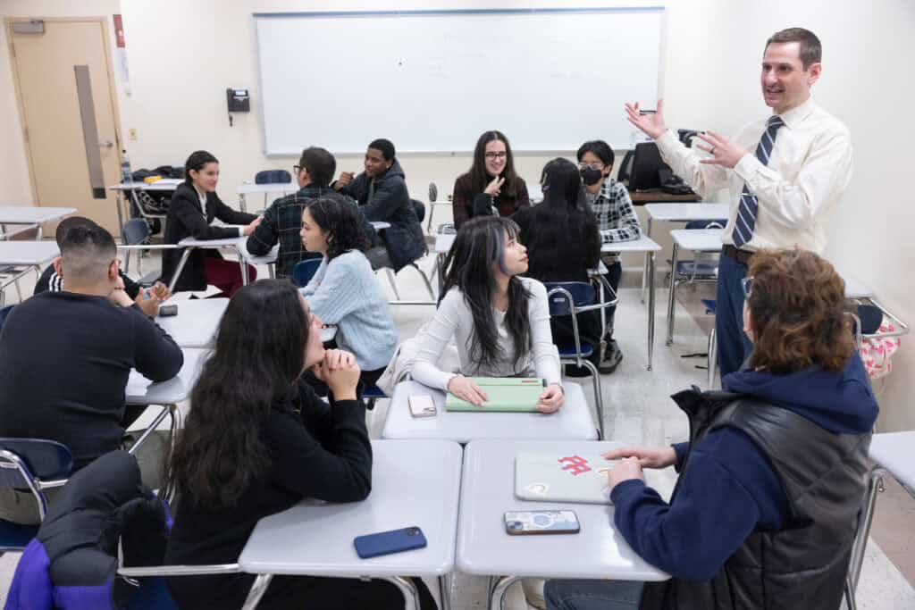 Diverse college students attending a classroom discussion with a teacher, promoting higher education, student engagement, and academic success.