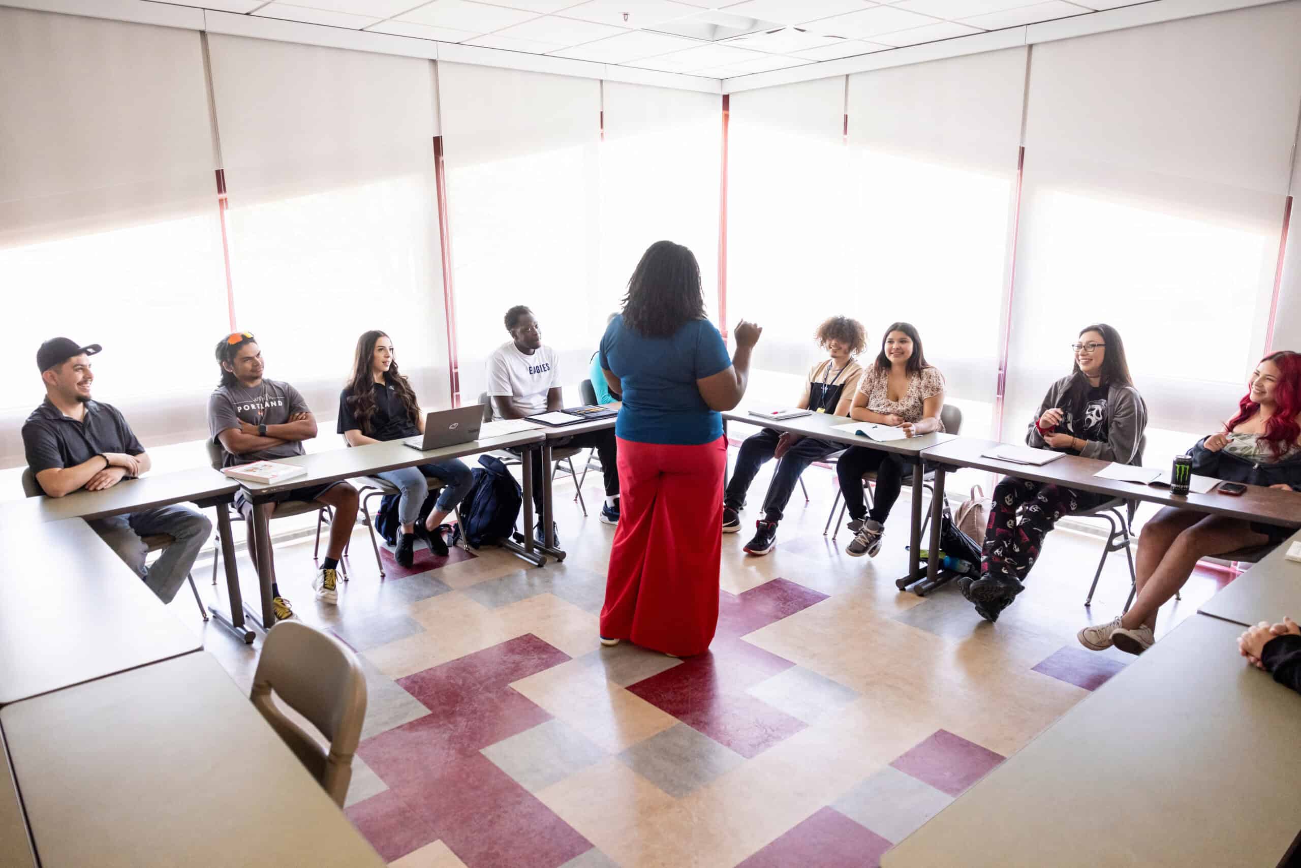 Black woman educator teaching diverse college students in a seminar or workshop room focused on student success and higher education initiatives.
