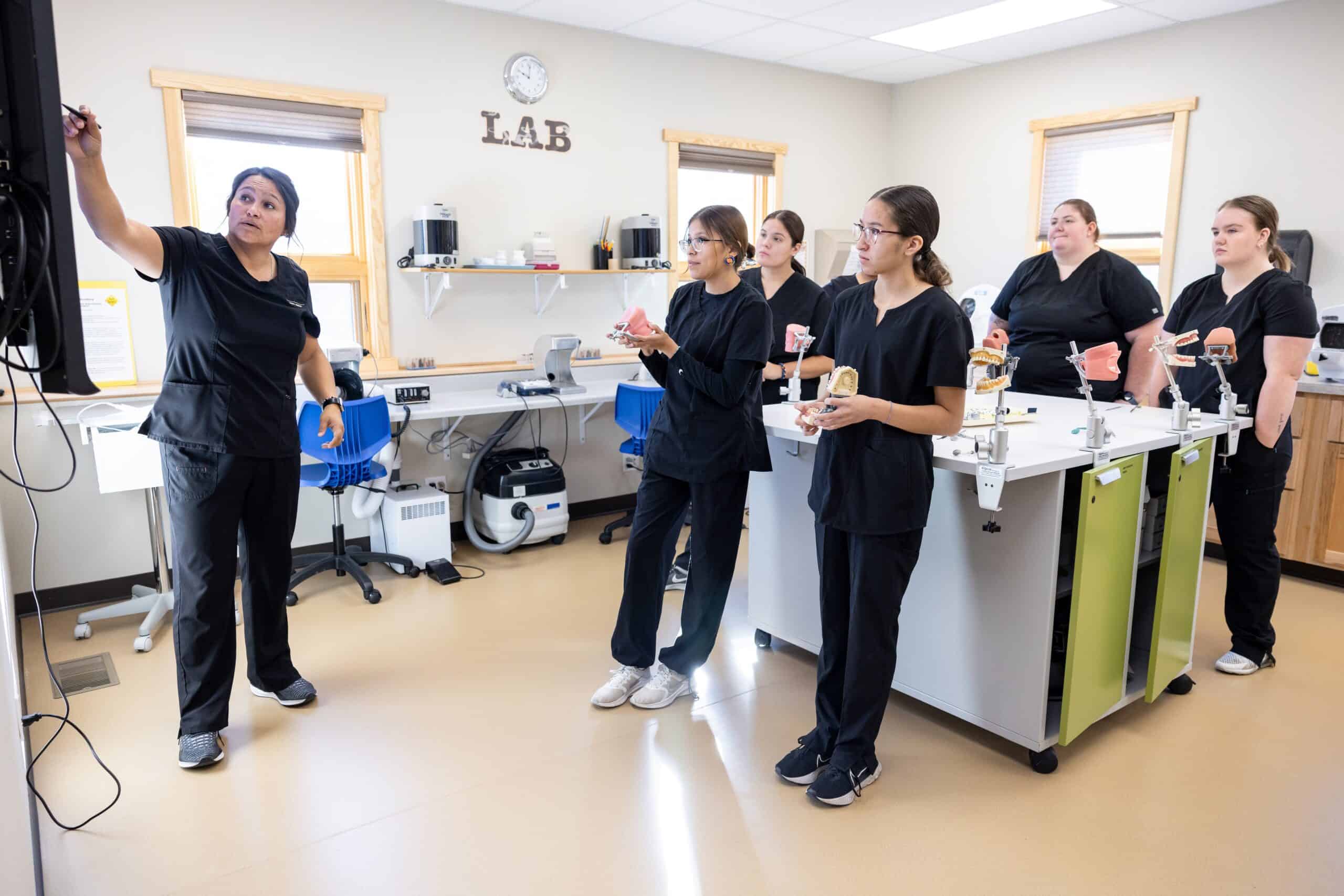 Dental hygiene students in a classroom with dental models during a training session.