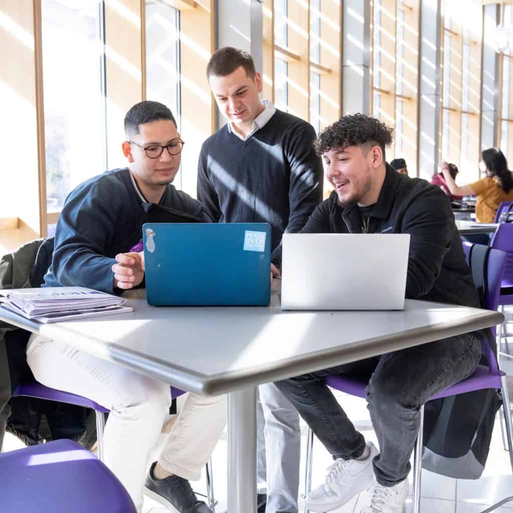 Students collaborating on laptops in a modern college campus study area for improving higher education success.