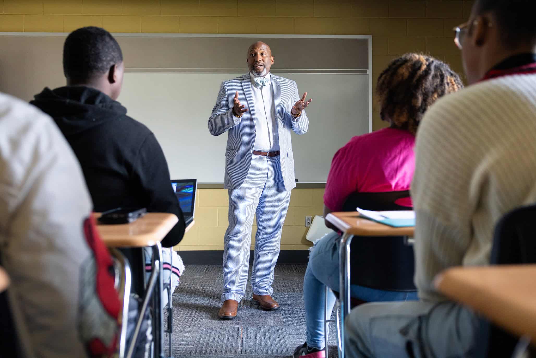 College instructor engaging diverse students in a classroom setting to promote completion of college education and success.