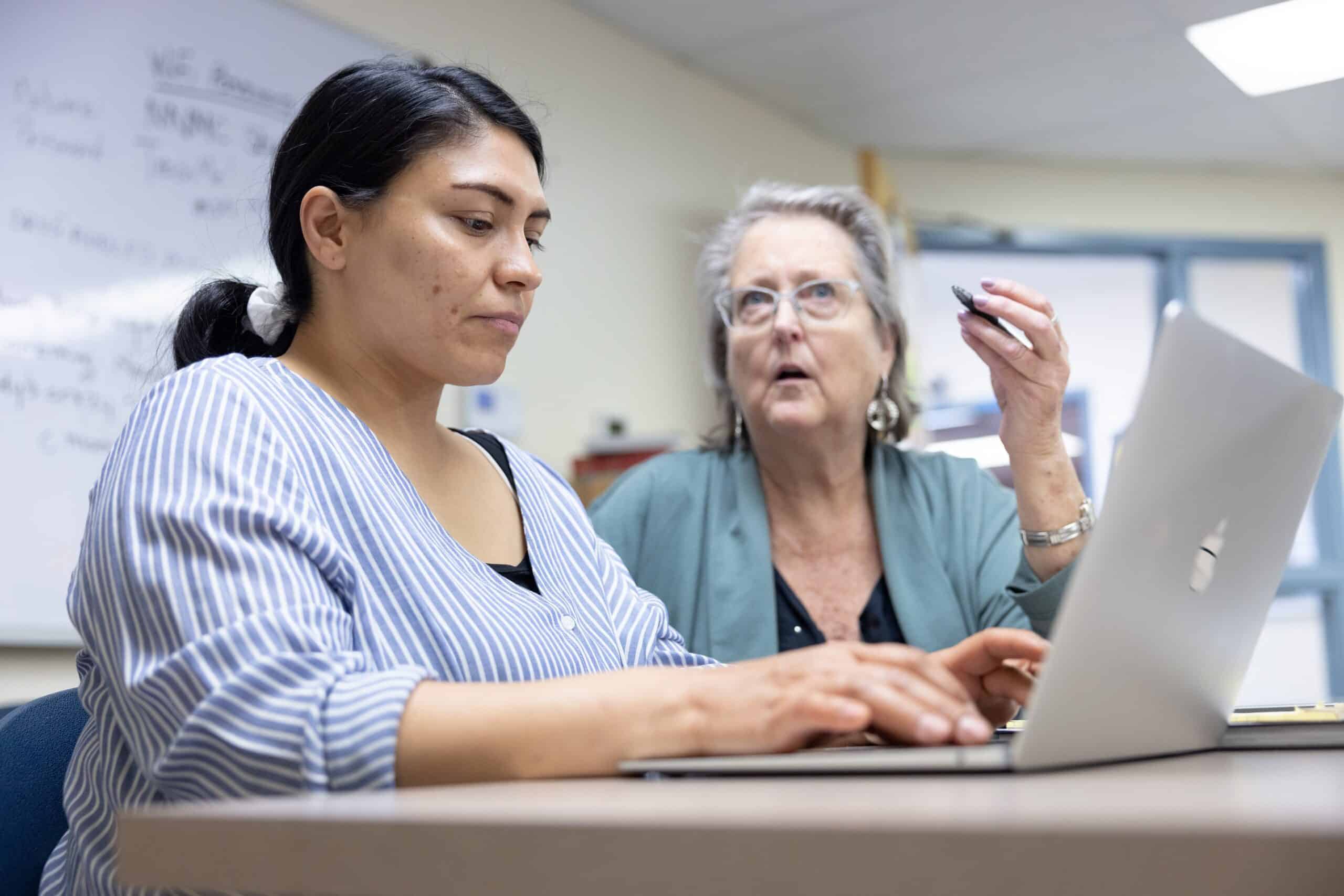 Highly engaged student and instructor collaborating on a laptop during a college class or educational workshop focusing on higher education success and college readiness.