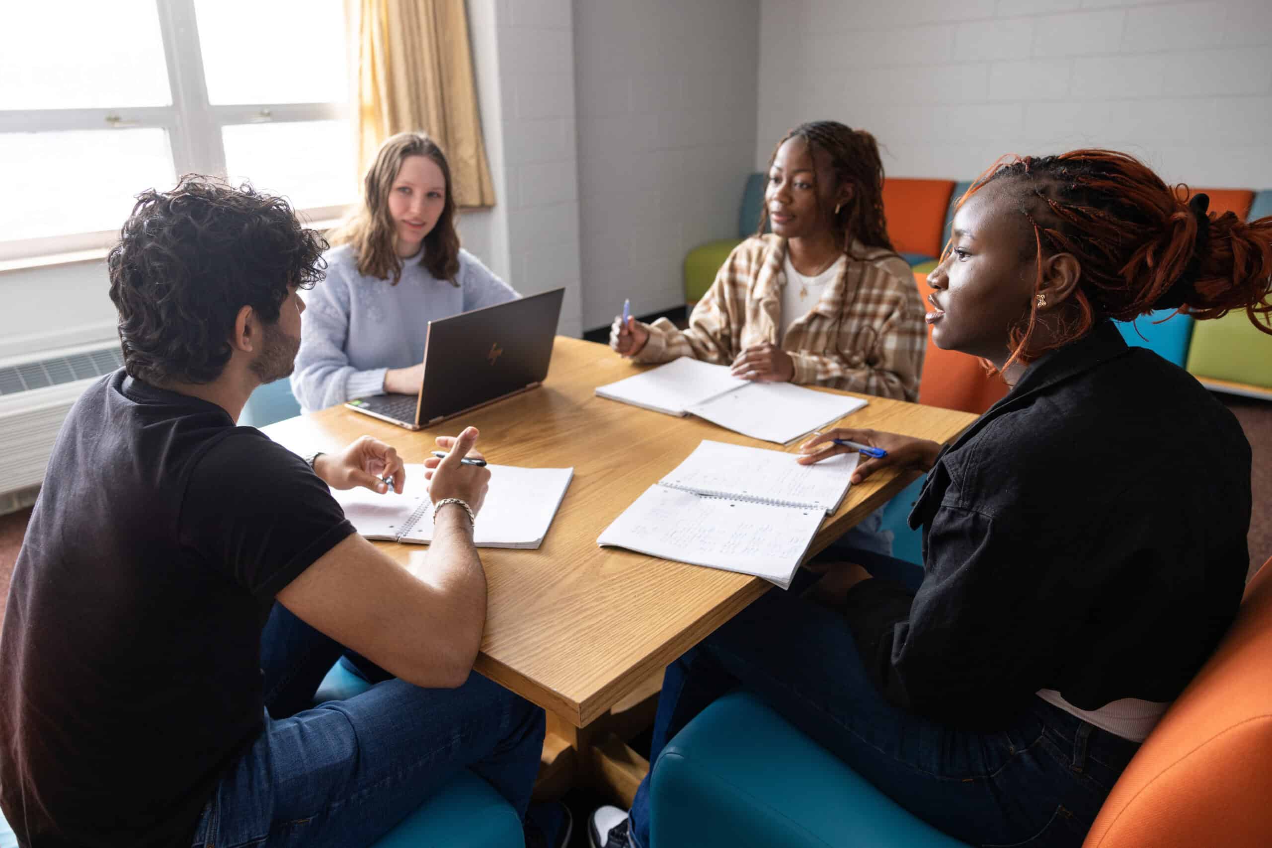 High school students and a counselor having a college planning meeting at a table, promoting college readiness and success strategies for diverse students.