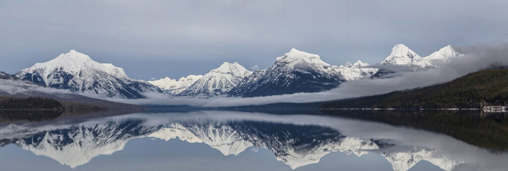 Snow-capped mountains reflected in a calm lake, representing natural beauty and academic excellence in higher education.