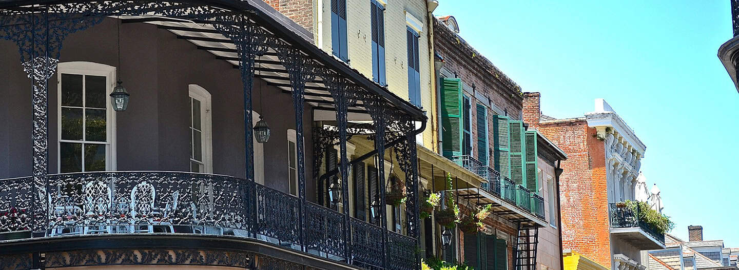 Balcony with ornate wrought iron railing on historic building, colorful cityscape, residential architecture, vibrant neighborhood, charming urban scene.