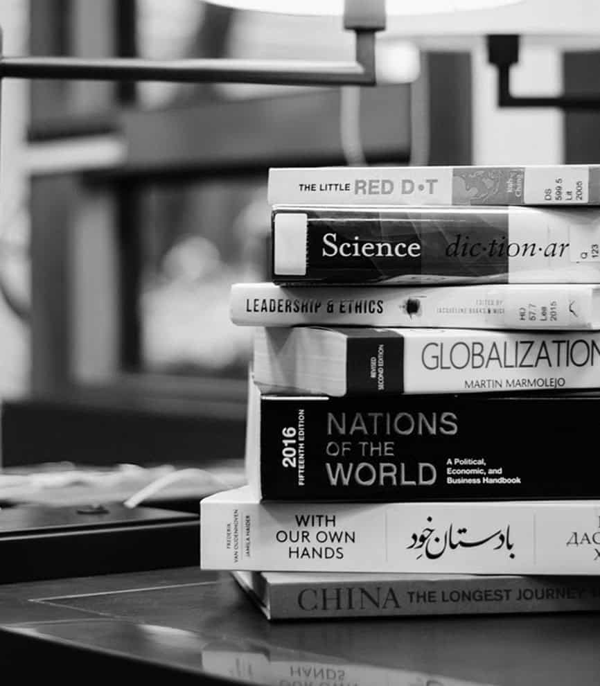 Books on global history and politics stacked on a desk, including titles like "Nations of the World" and "Globalization," representing educational resources vital for college students and academics.
