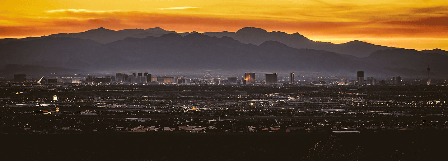 Complete College America city skyline at sunset with mountains and illuminated urban landscape, emphasizing education and community development.