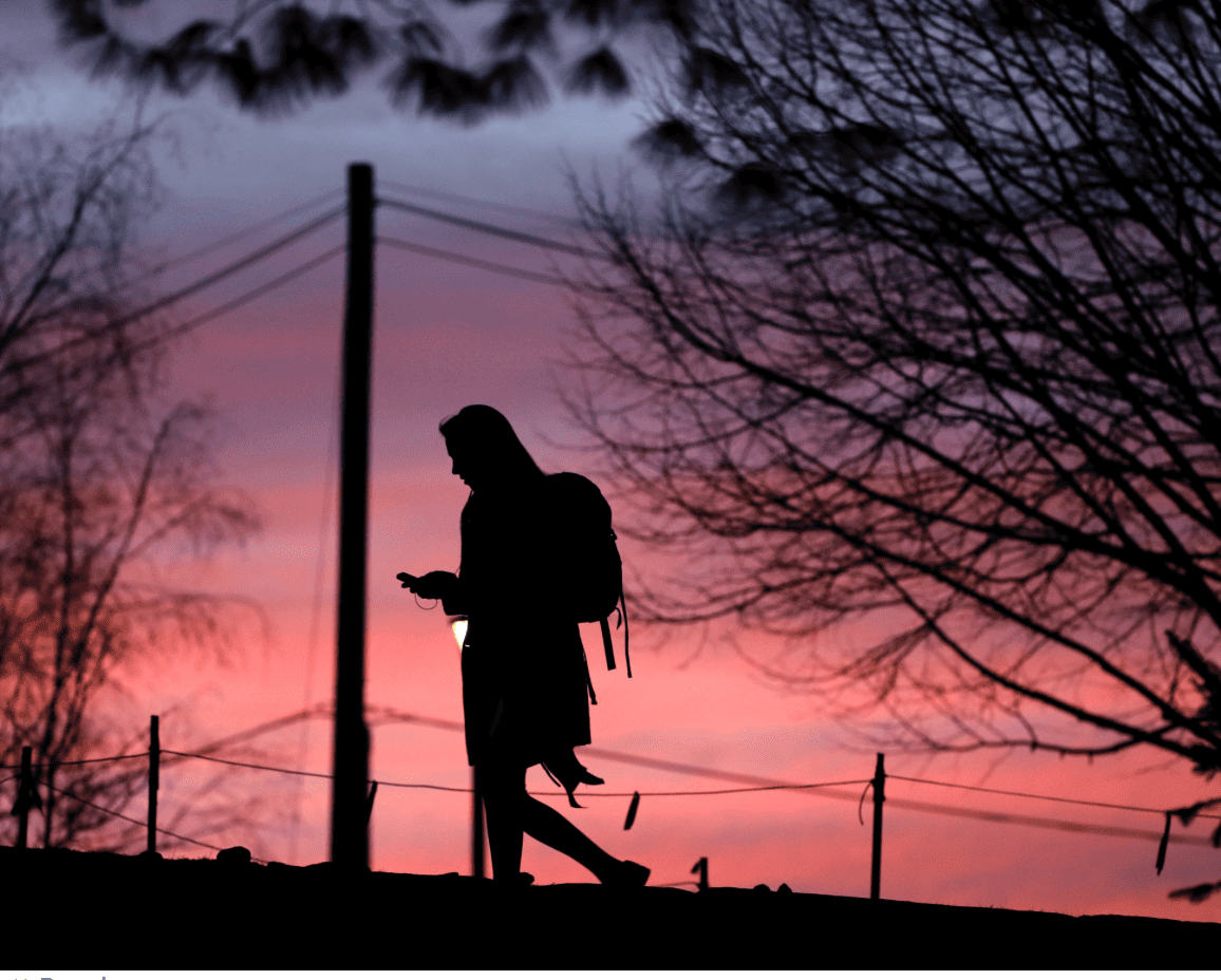 Student silhouette walking outdoors at sunset for Complete College America initiative.