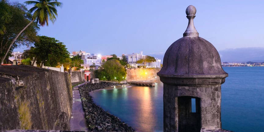 Historic coastal fortress during twilight with Caribbean architecture and lush greenery in San Juan, Puerto Rico.