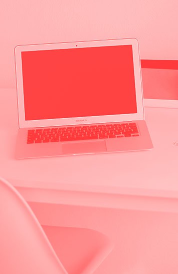 Bright pink laptop on desk with keyboard visible, showcasing modern digital technology and online learning tools used in higher education.