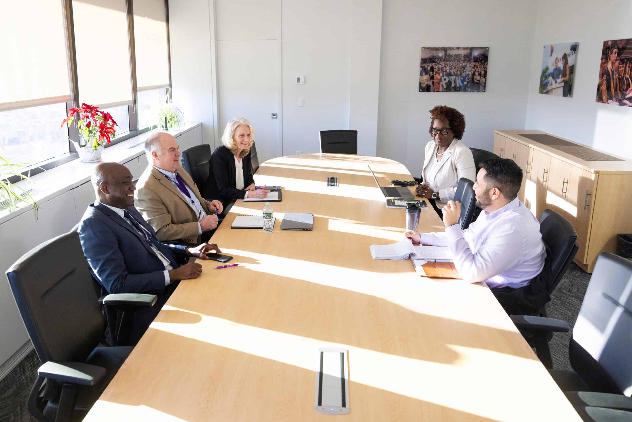 Diverse group of professionals having a meeting in a modern conference room with natural sunlight and colorful artwork on the walls.