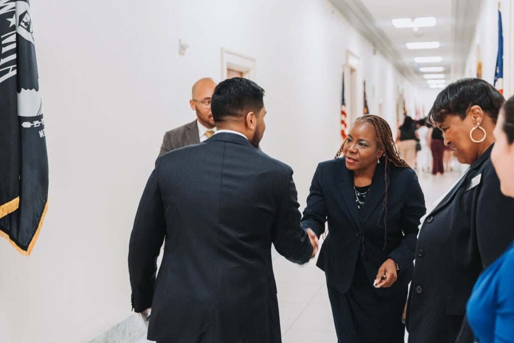 Professional handshake at Complete College America event promoting higher education reform and student success strategies.