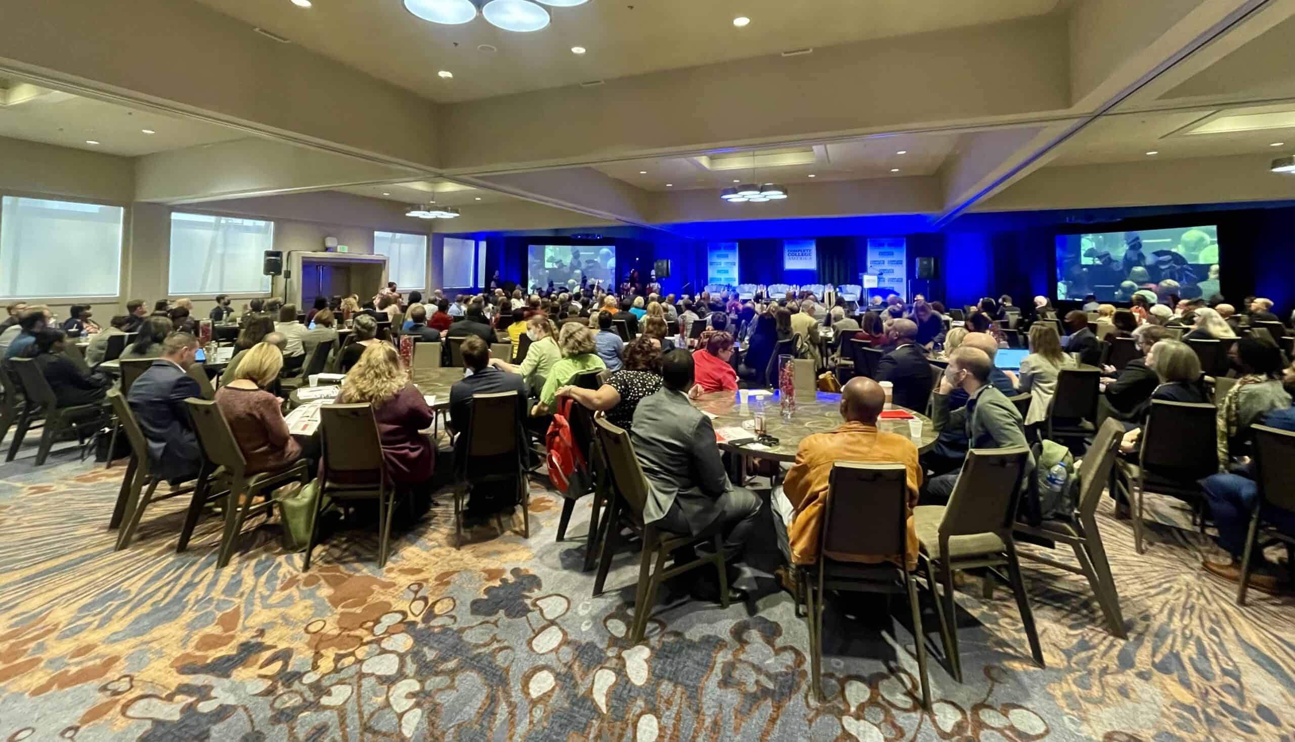 Efficient college conference with diverse attendees engaging in discussions and keynote presentations on higher education strategies and student success.