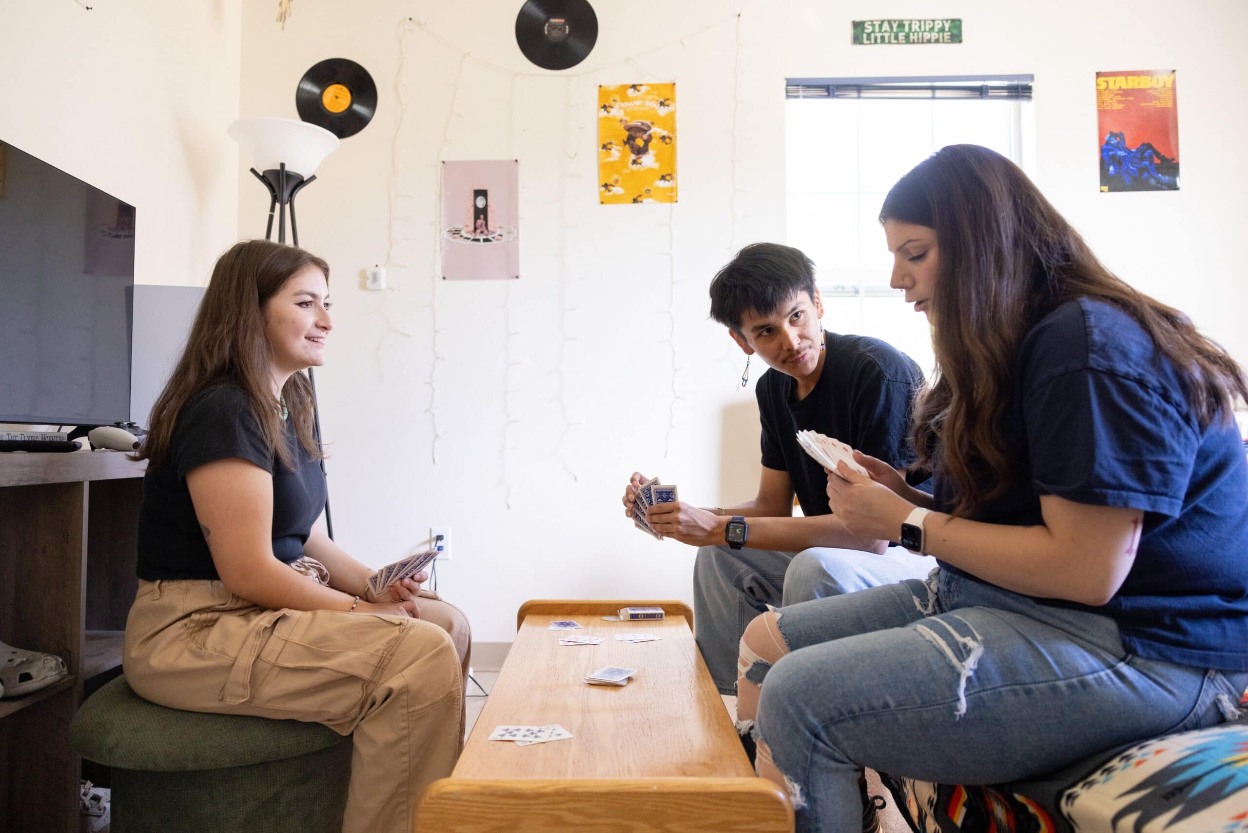 Students playing cards in a dorm room on a college campus.