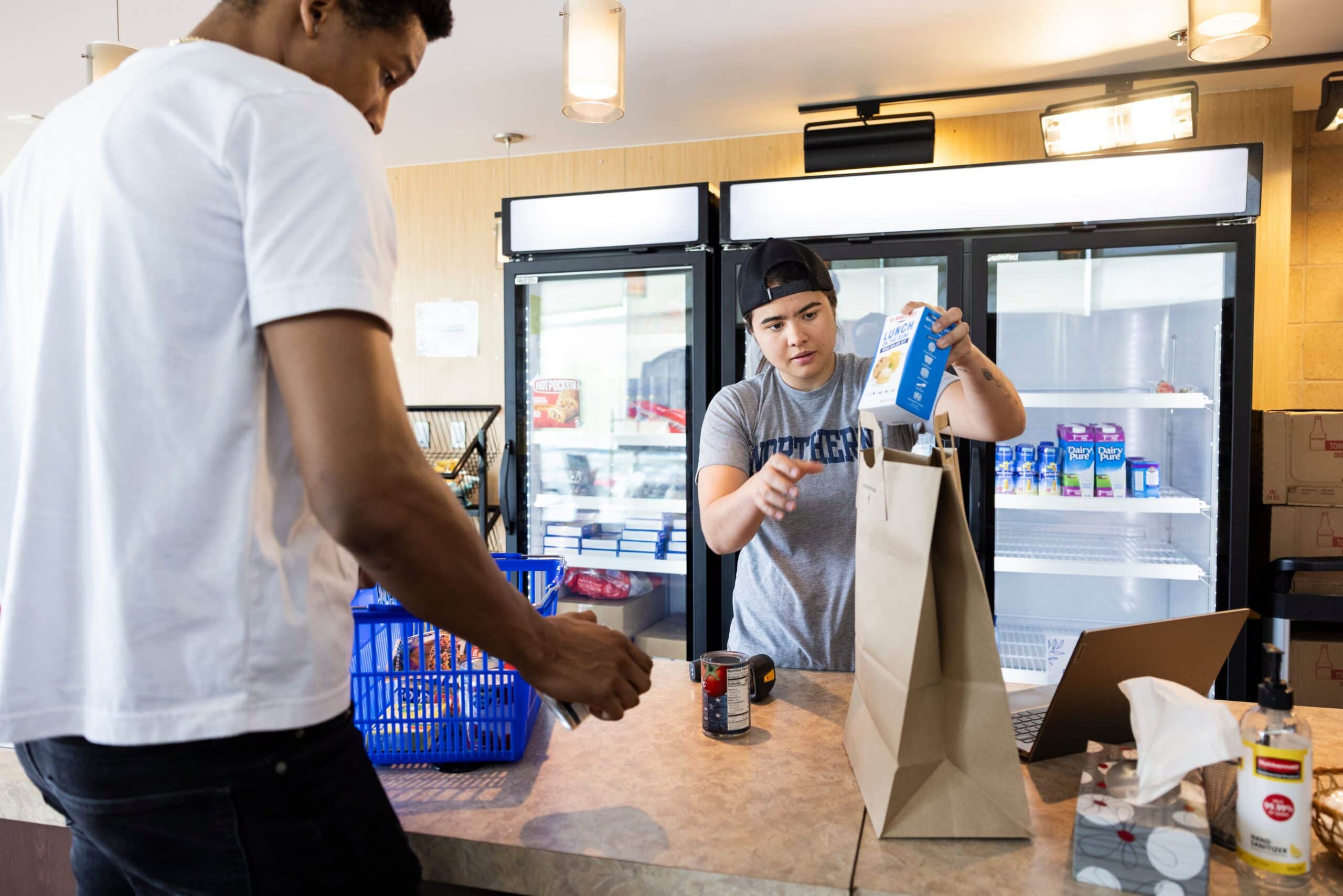 Student worker places item in a bag at a campus food pantry